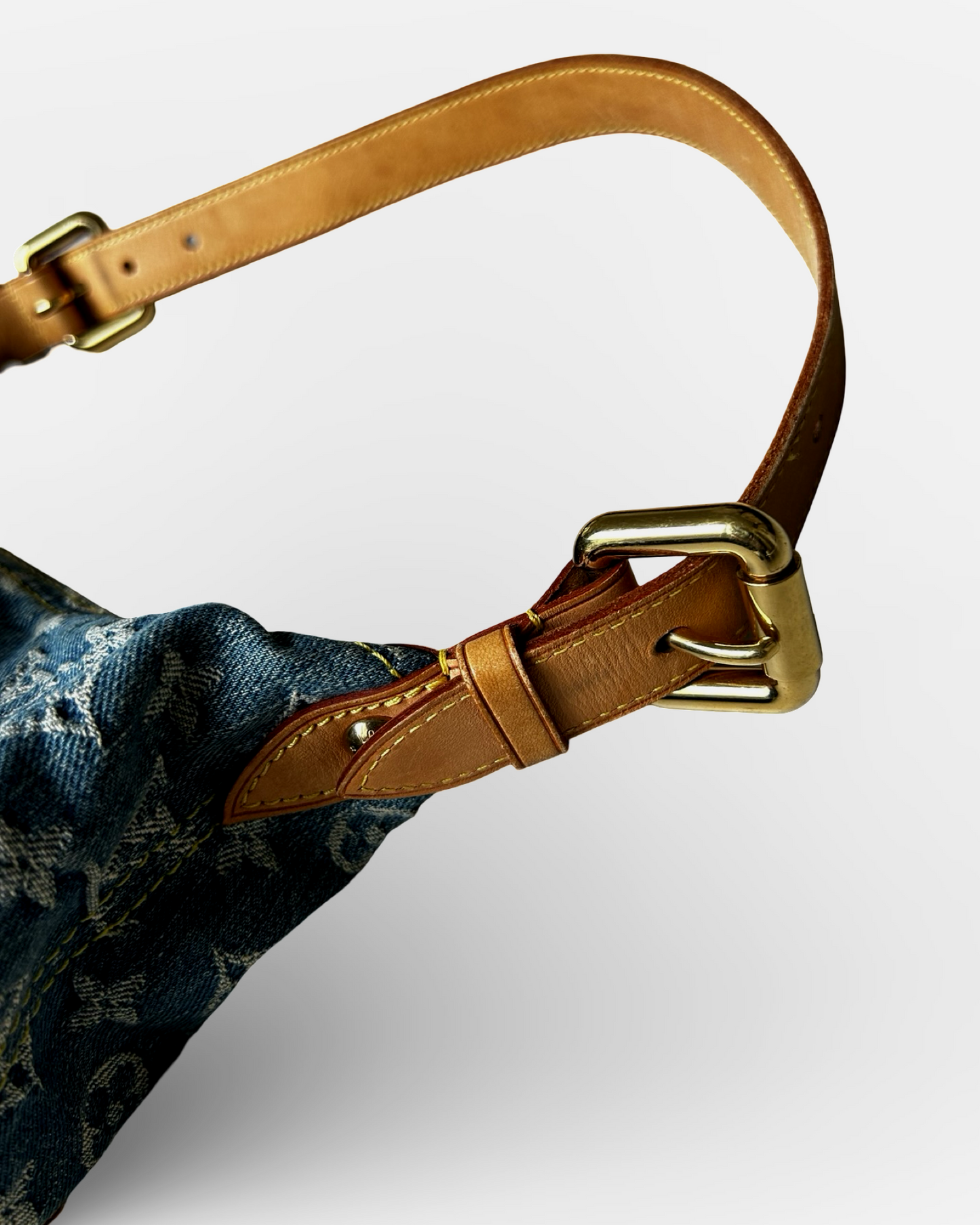 Louis Vuitton Monogram Denim Baggy GM Shoulder Bag adjustable leather strap detail with gold-tone buckle.